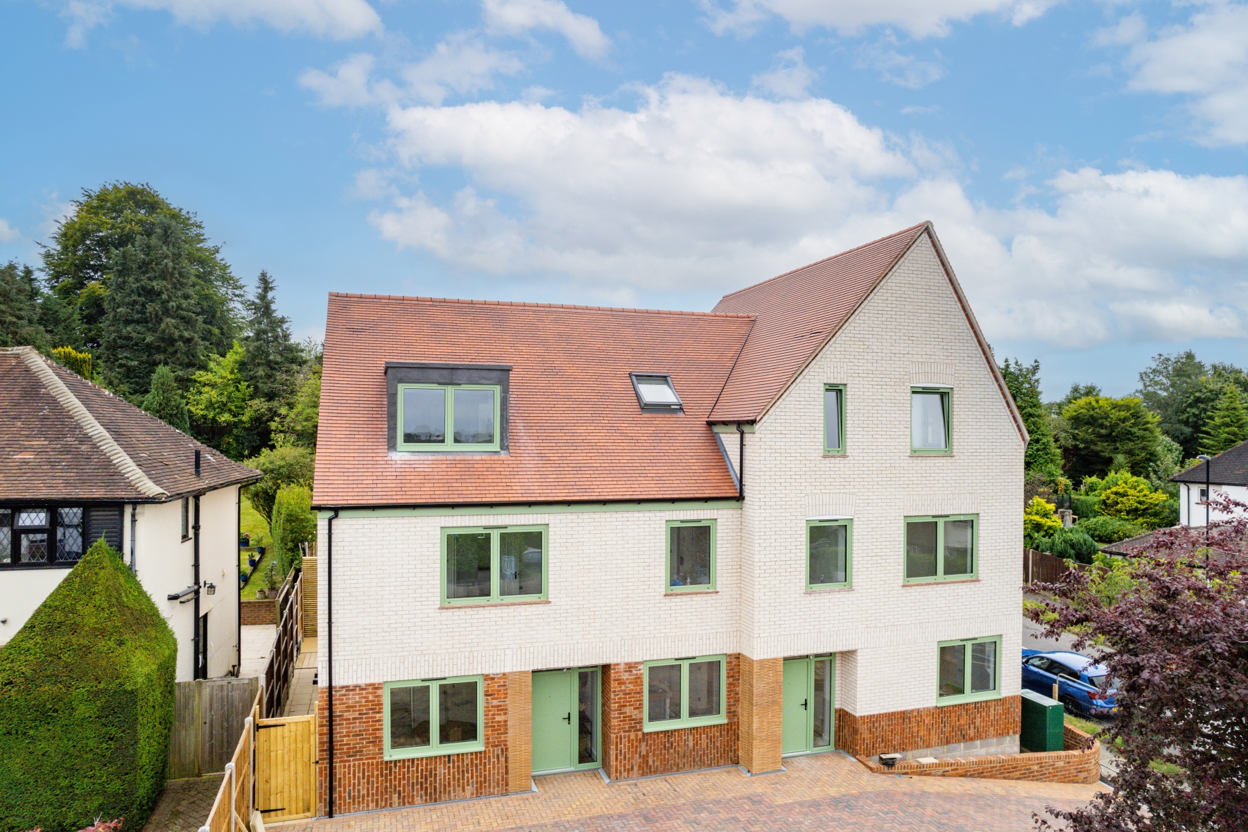 Street view of the new-build housing development at 158 Purley Downs Road, South Croydon, with pitched roofs and surrounding trees.