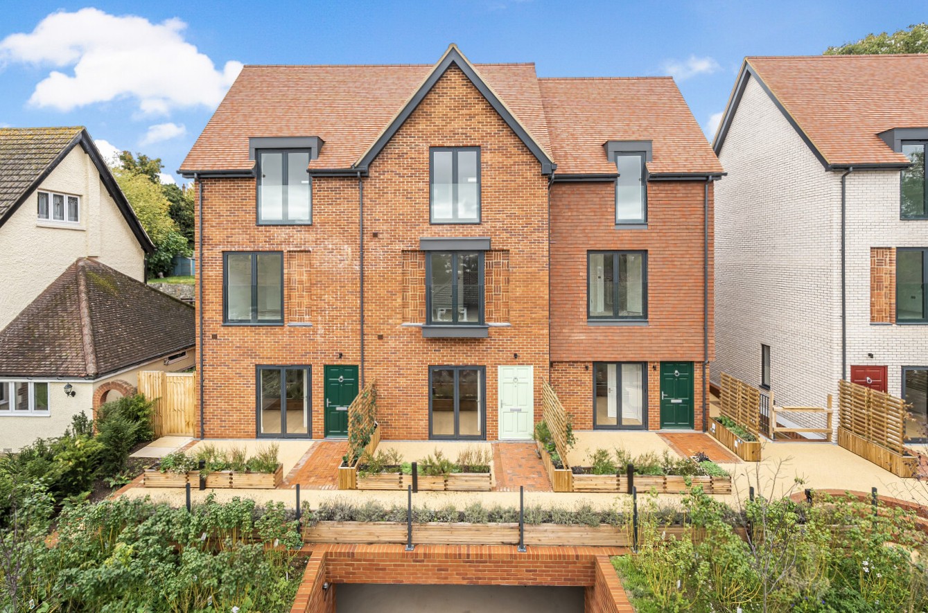 New-build houses in Coulsdon with gabled tiled roofs, brick and rendered façades, private terraces and landscaped outdoor areas.