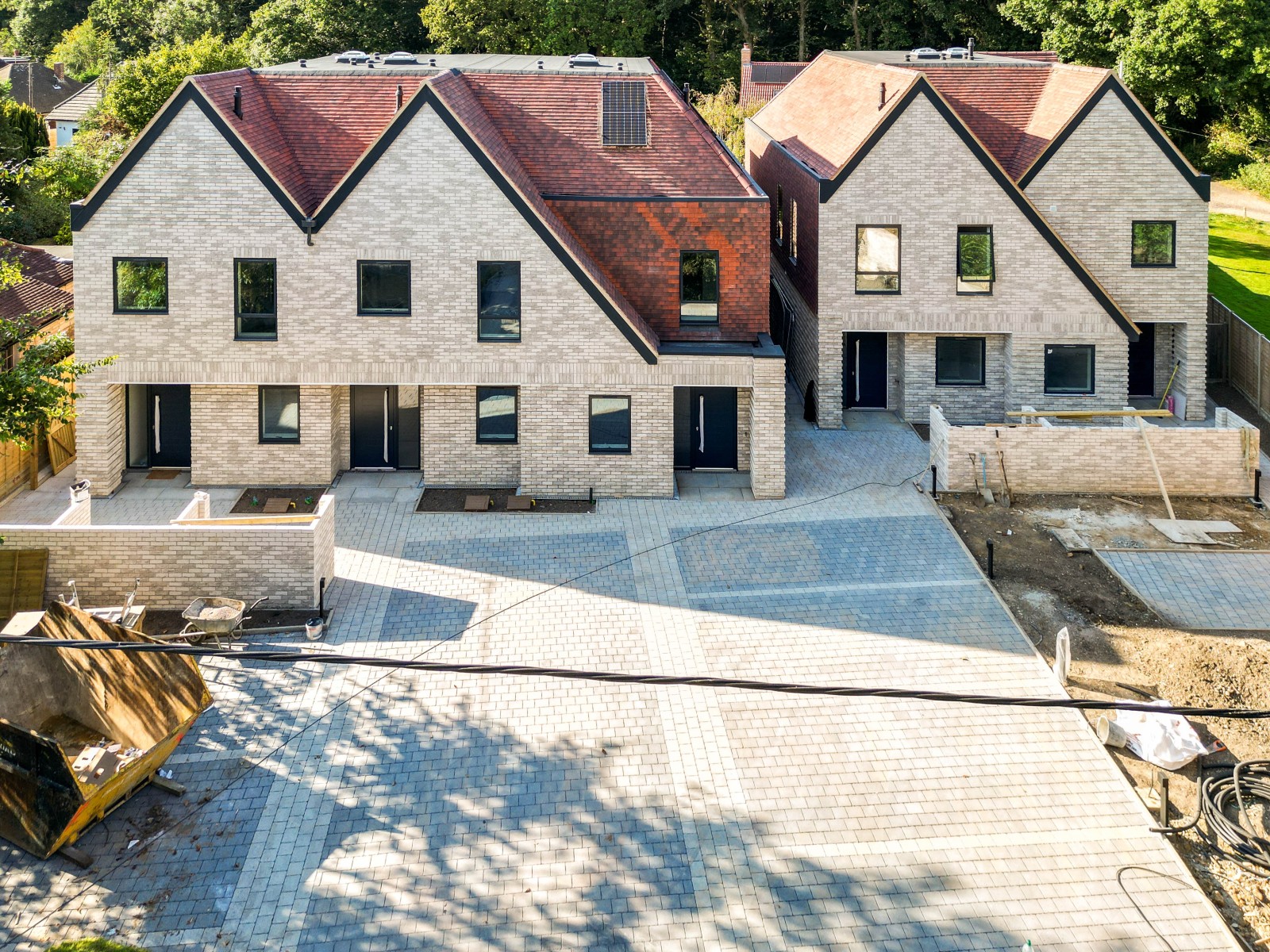 Five new-build five-bedroom houses in Warlingham, Surrey, with gabled roofs, pale façades and paved driveways.