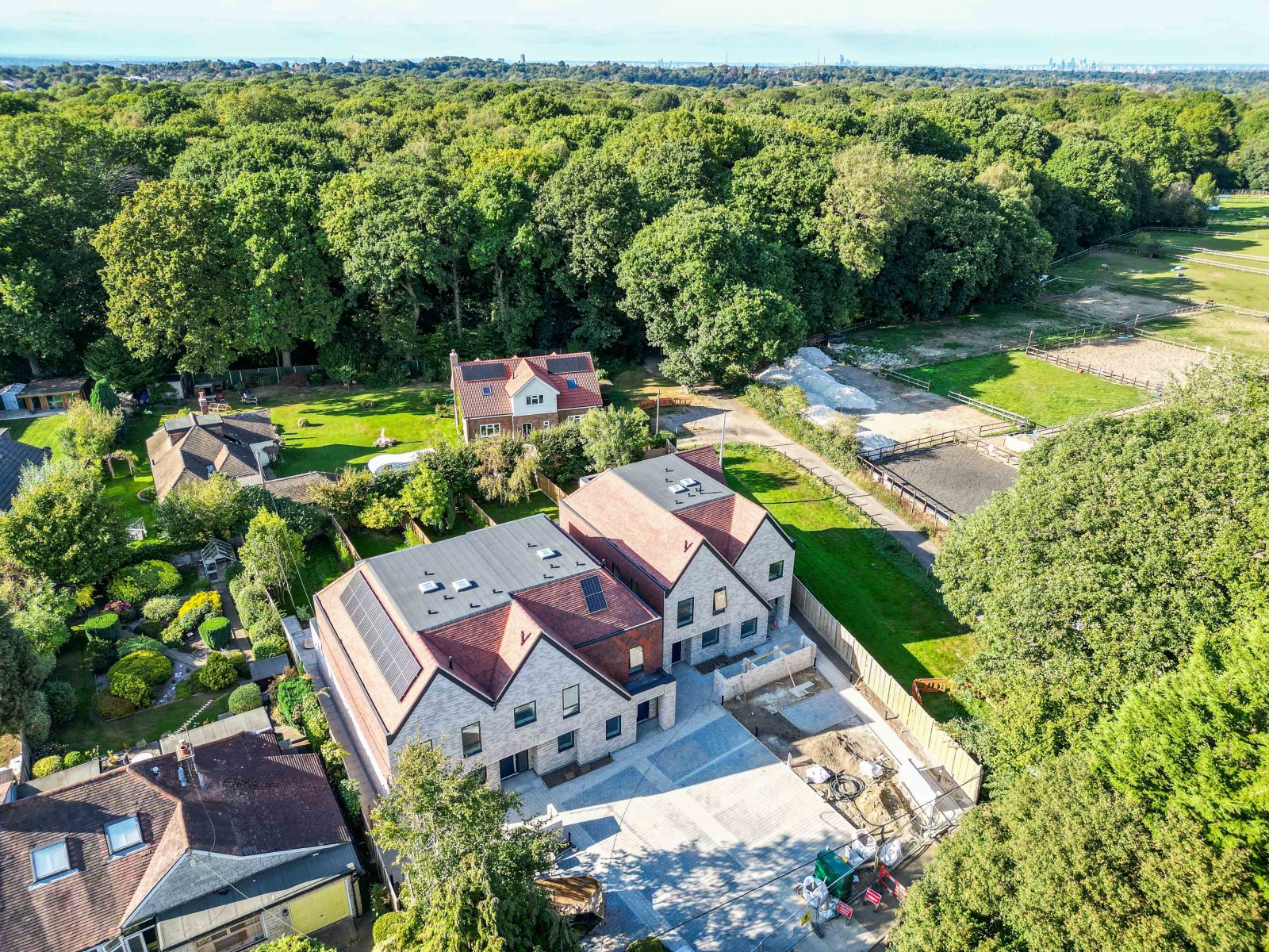 Five new-build five-bedroom houses in Warlingham, Surrey, with gabled roofs, pale façades and paved driveways.