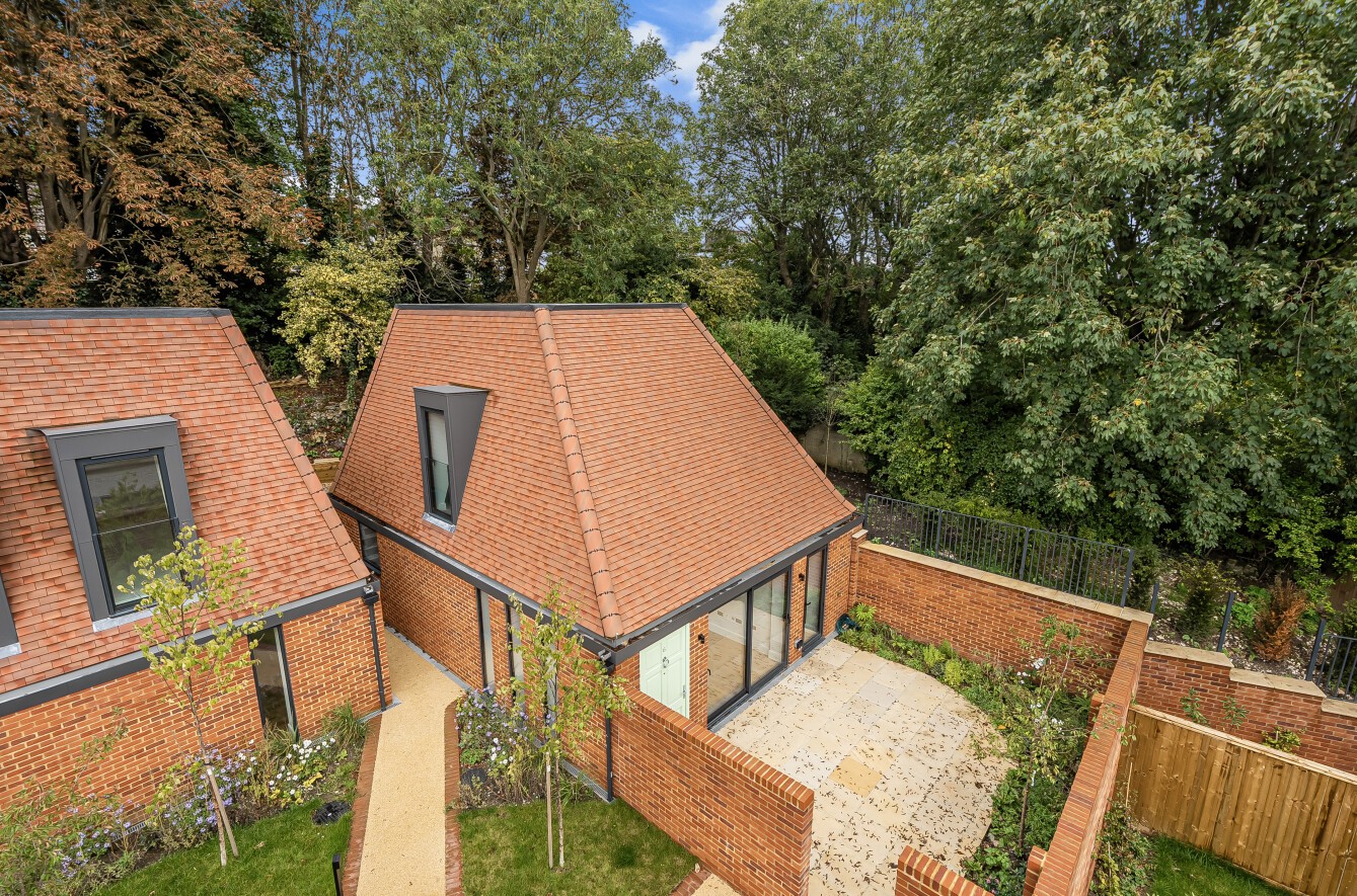 New-build houses in Coulsdon with gabled tiled roofs, brick and rendered façades, private terraces and landscaped outdoor areas.