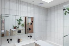 Contemporary bathroom with a large rooflight, white wall tiles, terrazzo bath surround and terracotta-coloured vanity.