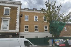 Front elevation of a new-build apartment development in Hackney, with yellow brickwork, white-framed windows