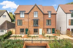 New-build houses in Coulsdon with gabled tiled roofs, brick and rendered façades, private terraces and landscaped outdoor areas.