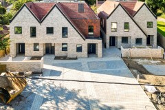 Five new-build five-bedroom houses in Warlingham, Surrey, with gabled roofs, pale façades and paved driveways.