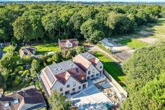 Five new-build five-bedroom houses in Warlingham, Surrey, with gabled roofs, pale façades and paved driveways.