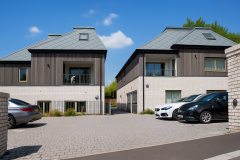 Modern apartment buildings with timber cladding, zinc shingle roofs, recessed balconies and a paved parking courtyard.