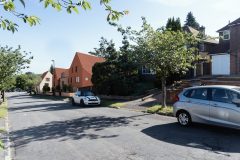 Street view of the new-build housing development at 158 Purley Downs Road, South Croydon, with pitched roofs and surrounding trees.