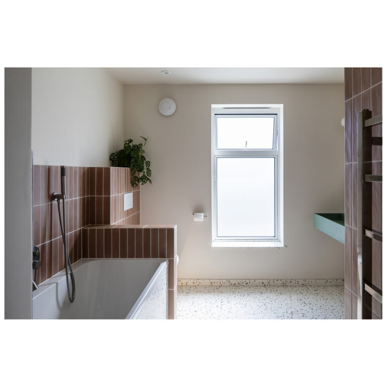 Bathroom with terrazzo flooring and wall finishes, terracotta tiles and a fitted bath