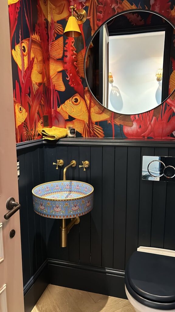 Downstairs cloakroom with fish-print wallpaper, dark panelling, patterned basin and brass taps, Battersea SW11