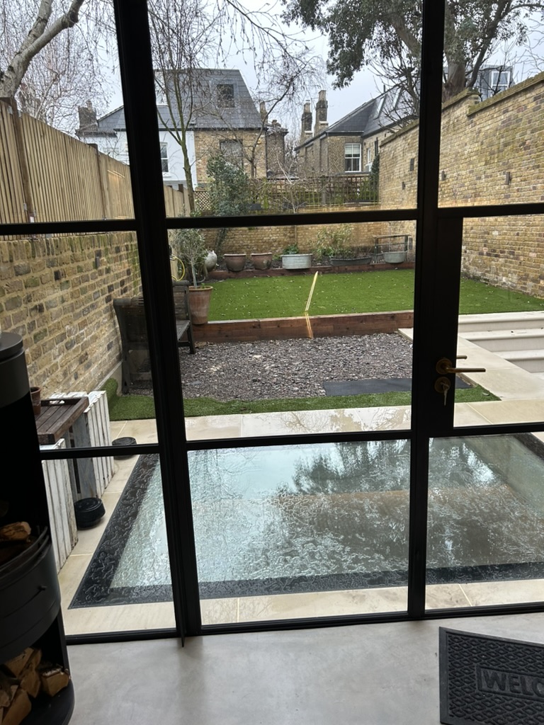 View through Crittall doors to the garden and walk-on glass rooflight over the new basement, Battersea SW11