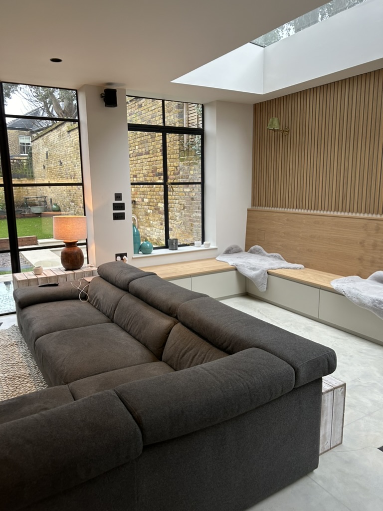 Living room with oak slatted wall panelling, built-in bench seating and rooflight in Victorian house renovation, Battersea SW11