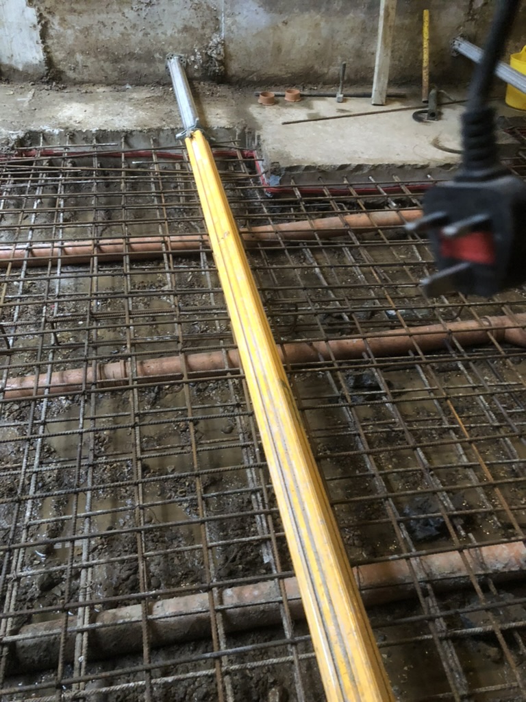 Basement slab reinforcement mesh laid over below-ground drainage pipes