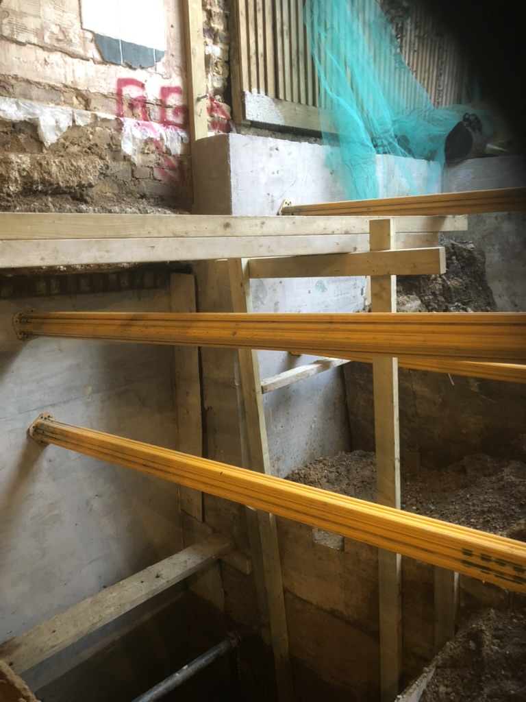 Numbered underpinning bays cast in sequence, with temporary propping across the basement excavation