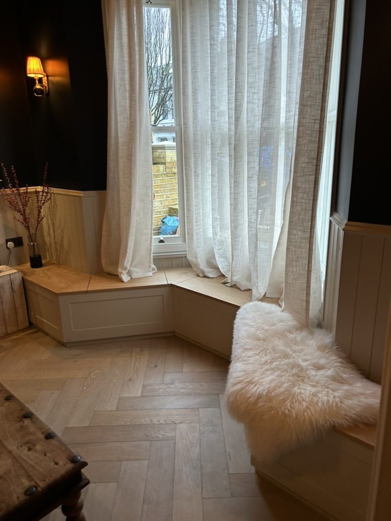 Bespoke built-in window seat around the original bay window in the snug