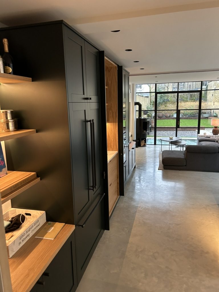 Deep green Shaker kitchen cabinetry with oak internals and open shelving