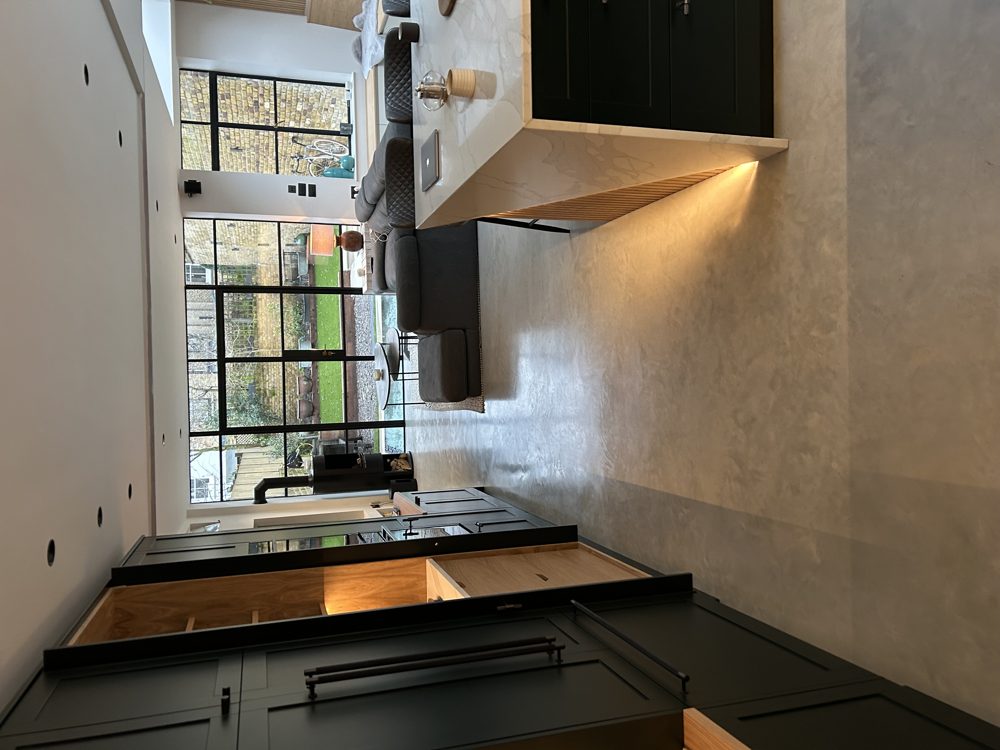 Open-plan kitchen and living space with poured concrete floor and steel-framed glazing to the garden